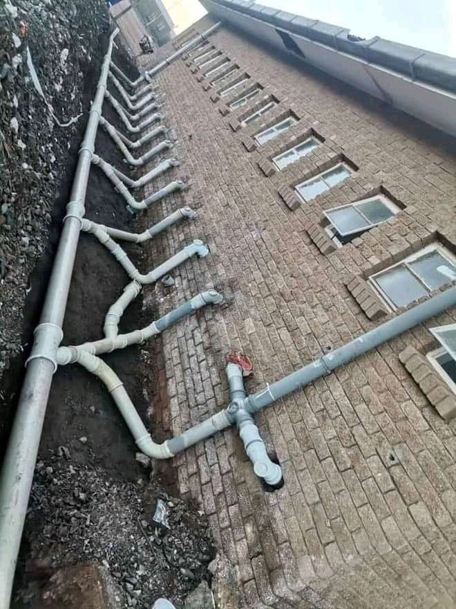 Drainage pipes with branches running along the outside wall of a brick building