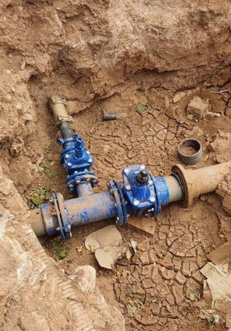 Blue gate valves on a water pipe in an excavated trench